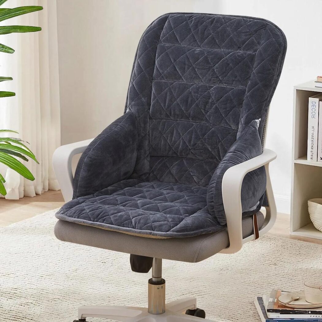 Photo d'un coussin gris foncé en velours placé sur une chaise de bureau beige à accoudoirs dans une pièce claire