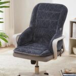 Photo d'un coussin gris foncé en velours placé sur une chaise de bureau beige à accoudoirs dans une pièce claire