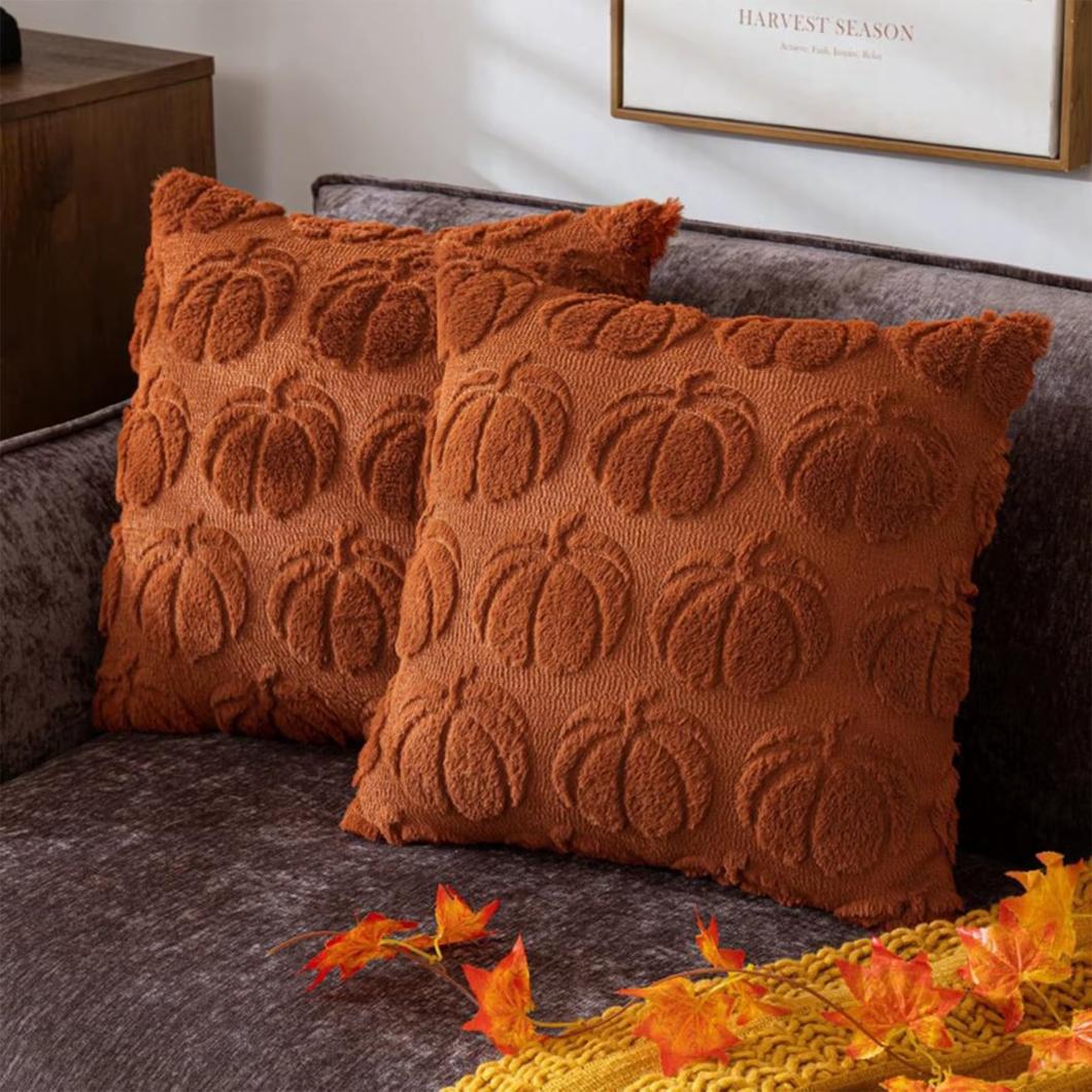 Photo de deux housses de coussin en velours citrouilles en relief sur des coussins posés sur un canapé marron