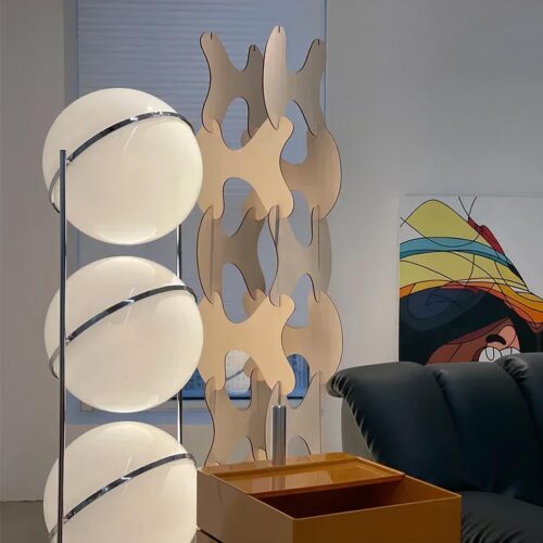 Photo d'une lampe design de style italien à trois grosses boules blanches cerclées d'acier dans un salon au canapé noir en cuir