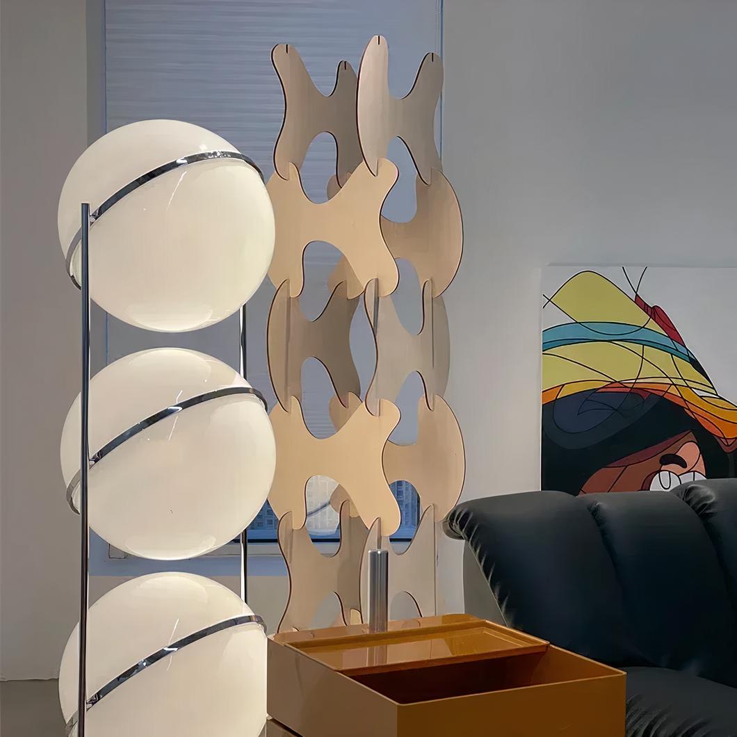 Photo d'une lampe design de style italien à trois grosses boules blanches cerclées d'acier dans un salon au canapé noir en cuir