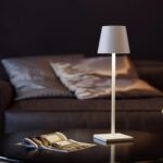 Photo d'une lampe à poser szans fil rechargeable blanche posée sur un chevet dans une chambre