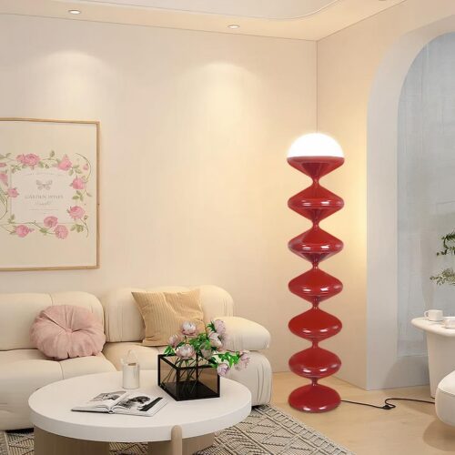 Photo d'une lampe de salon à poser rouge originale en forme de spirale dans un salon aux tons beige et blanc, au canapé et table basse blanche