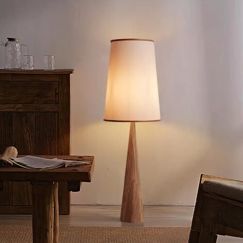 Photo d'une lampe design de style Wabi Sabi avec pied en bois et abat-jour en toile posé sur un sol ciré beige dans une salle à manger aux meubles en bois style campagnard