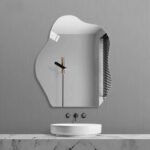 On voit une vasque et un miroir asymétrique adhésif en forme de nuage au dessus, sur un mur gris.