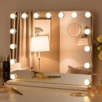 Dans une chambre à l'ambiance douce et tamisée, on voit un miroir rectangle avec des ampoules led tout autour.