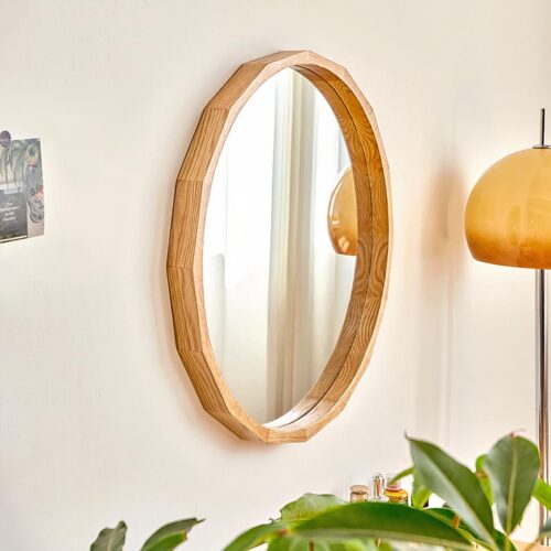 Miroir rond en bois sur mur beige avec plante