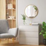 coin salon avec fauteuil gris, commode blanche ikéa et miroir rond doré