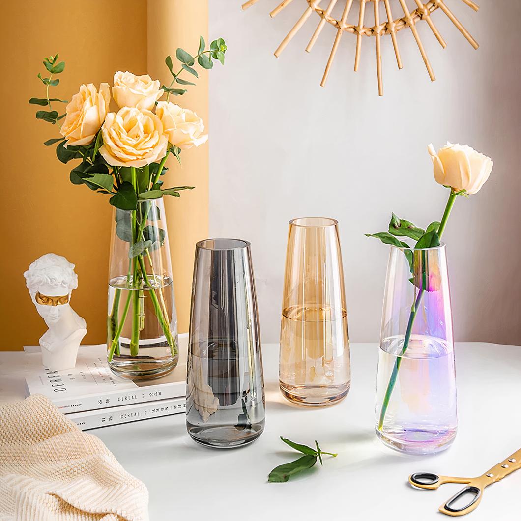 Quatre petits vases en verre avec deux contenant des fleurs.