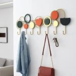 Porte-manteau mural à formes colorées avec des affaires pendues.