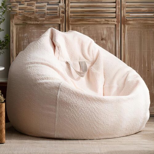 Photo d'un pouf en forme de poire en velours chenille blanc devant un meuble en bois clair