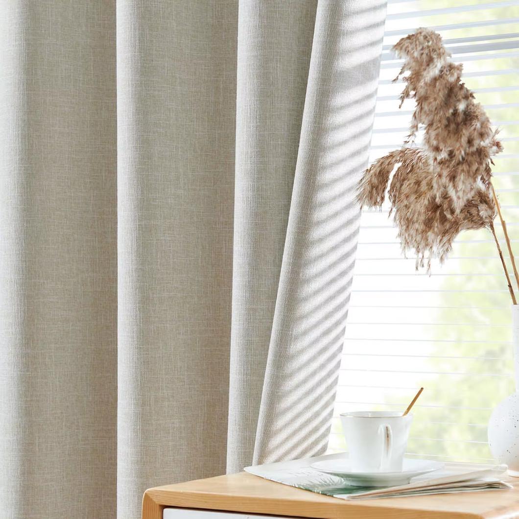 Rideau beige derrière une table en bois.