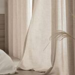 Rideau beige devant une fenêtre.