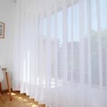 Rideau voilage blanc devant une baie vitrée.