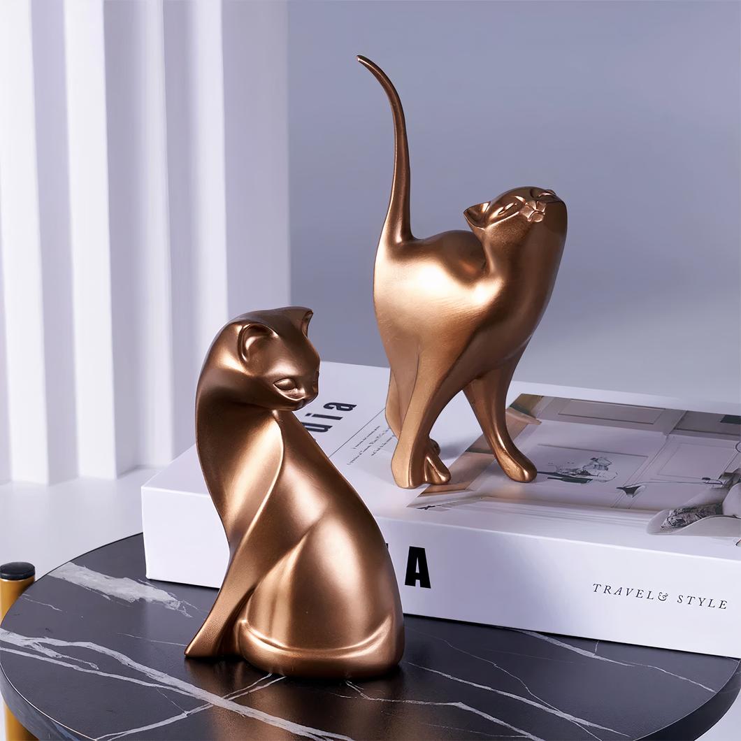 Deux statuettes chat doré sur un livre