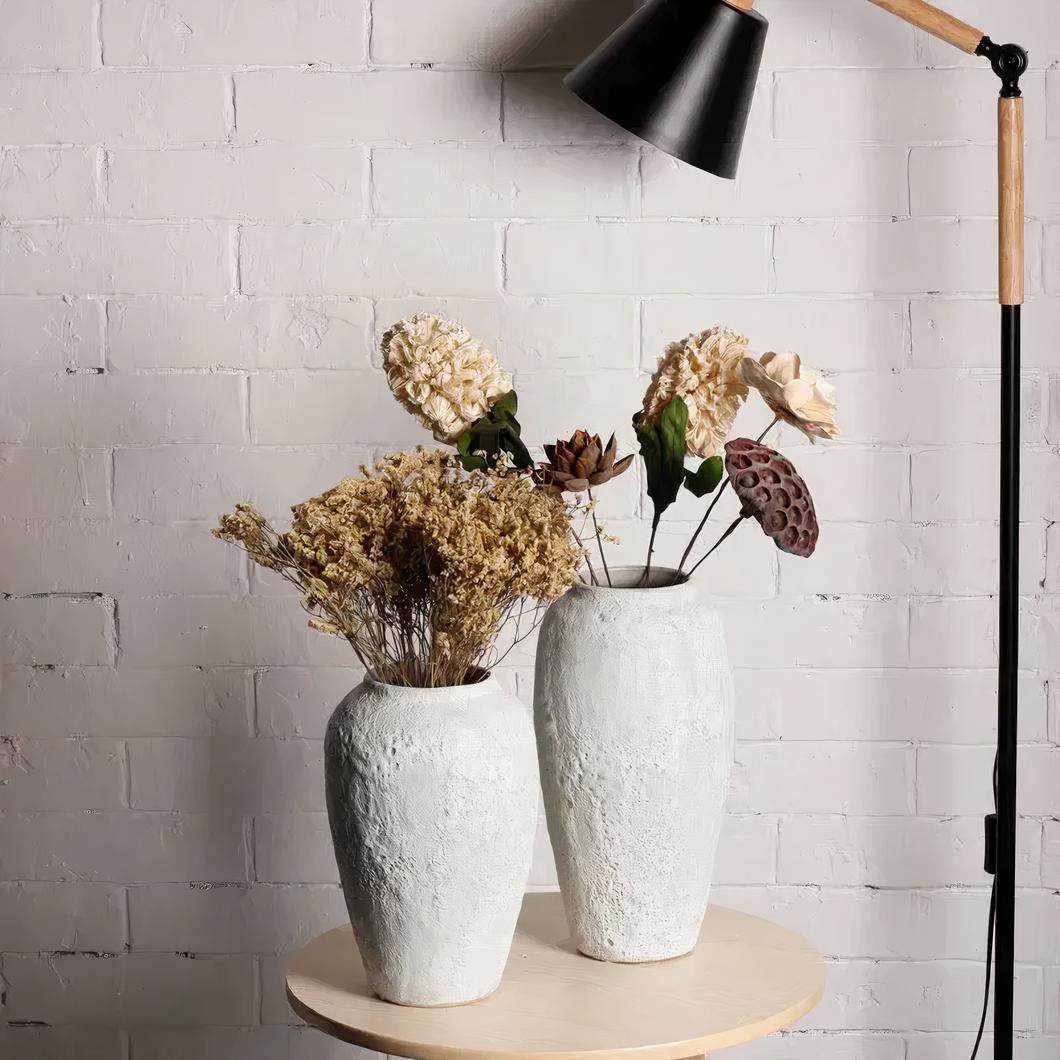 Vases blancs en céramiques posés sur une table et contenant des fleurs.