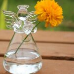 Vase en verre en forme d'ange avec une fleur orange.