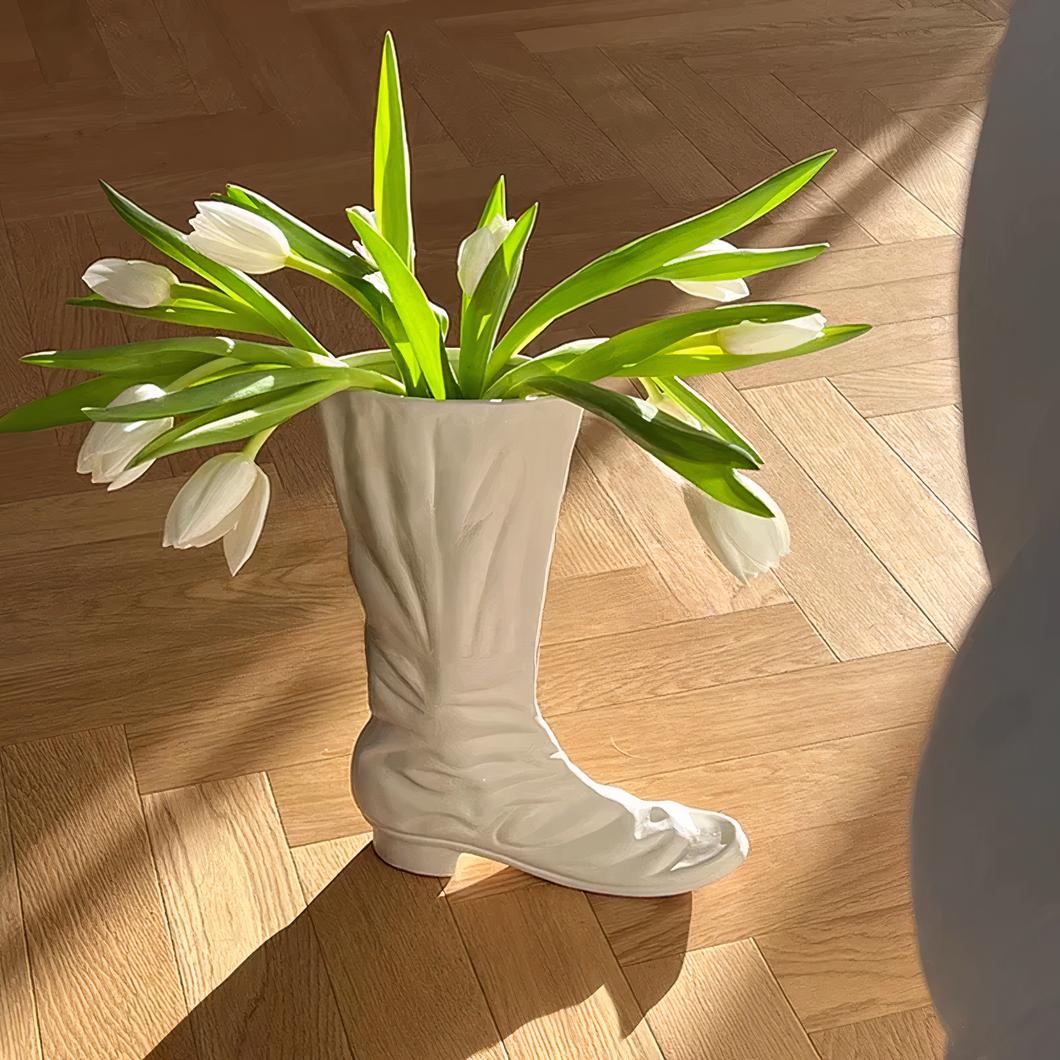 Vase en forme de botte avec des fleurs.