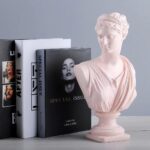 Statuette d'Aphrodite, couleur rose près de livres.