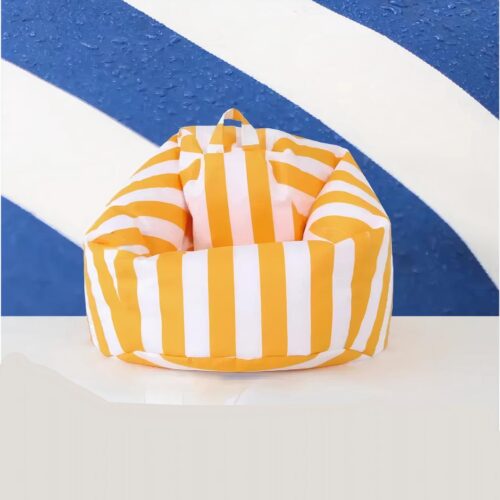 Photo d'un pouf d'extérieur rayé jaune et blanc devant un fond mural rayé bleu et blanc et un sol gris