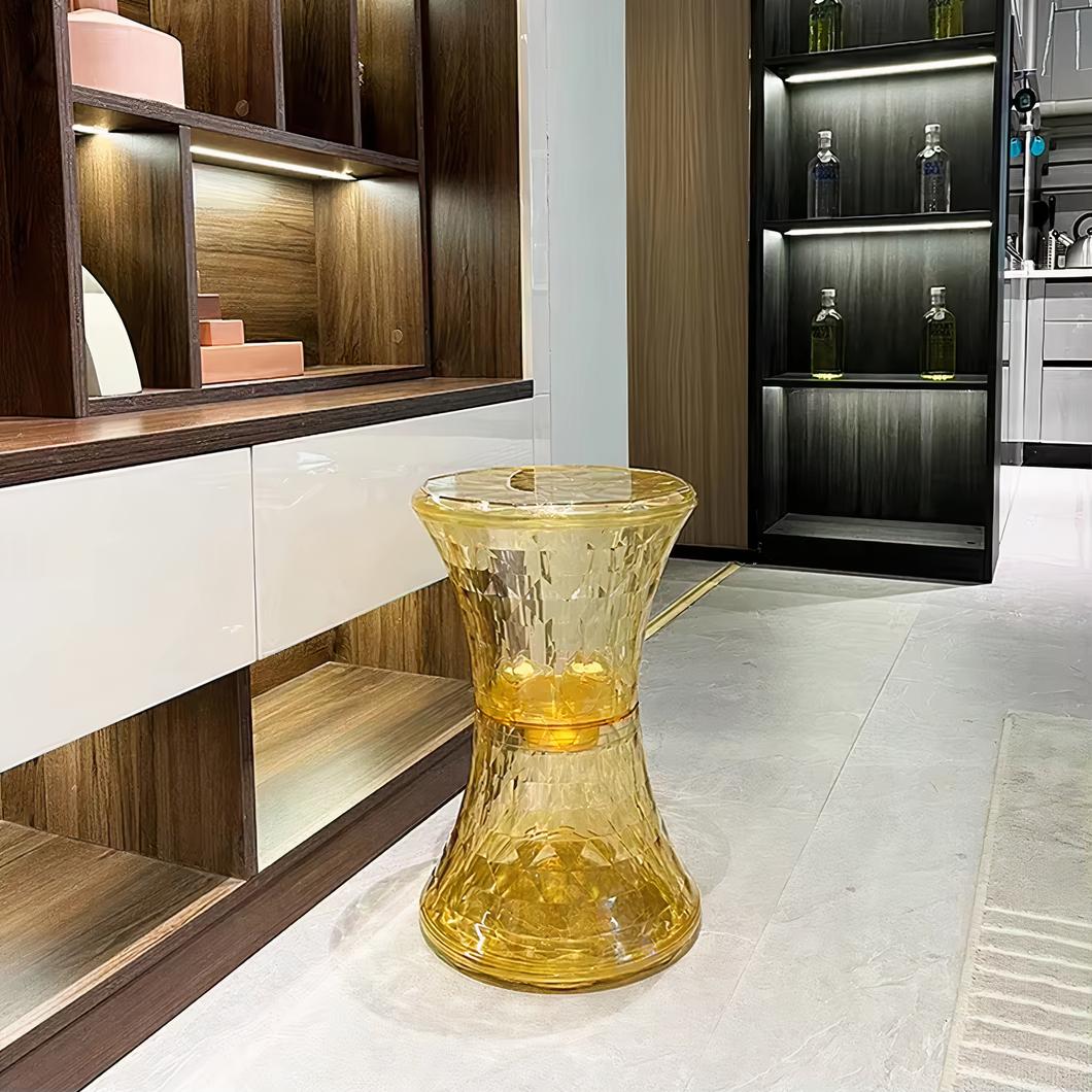 Photo montrant un pouf en plastique transparent jaune dans une pièce au style moderne sur un sol beige clair