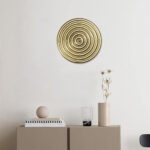 Décoration murale metal dore ronde sur un mur blanc dans une ambiance moderne zen